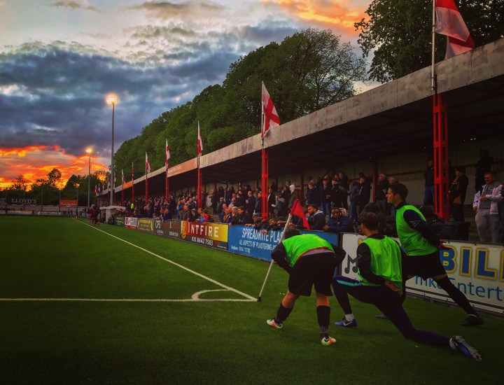 The sun sets as substitutes warm up during the Isthmian League Premier Division Play-Off Semi-Final at The War Memorial Sports Ground