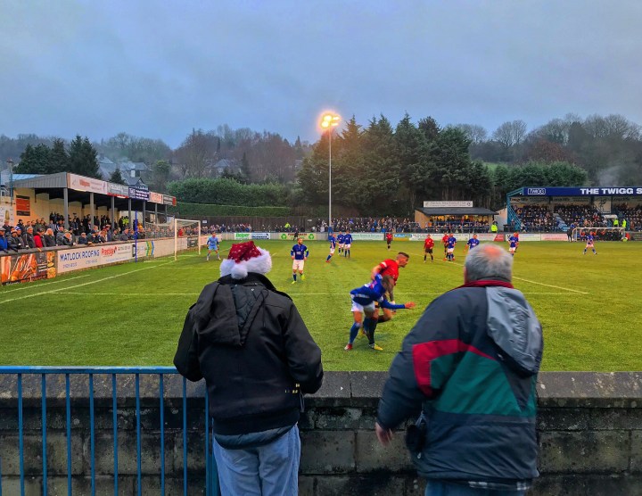 A fan in a santa hat watches the Boxing Day derby between Matlock Town and Buxton