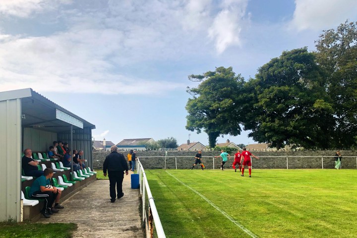 A Bodedern Athletic player keeps the ball in play against Ruthin Town, whilst ten supporters watch on from a small stand