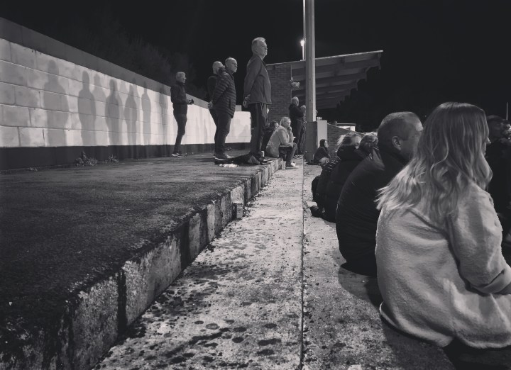Supporters watch a match from the terrace at Conwy Borough's Y Morfa ground