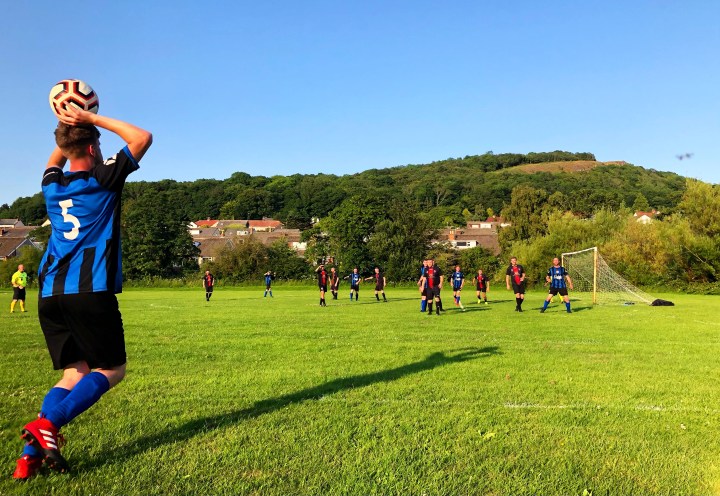 Betws-y-Coed's number 5 takes a long throw in against Rhos United on a sunny evening at Brookfield Drive