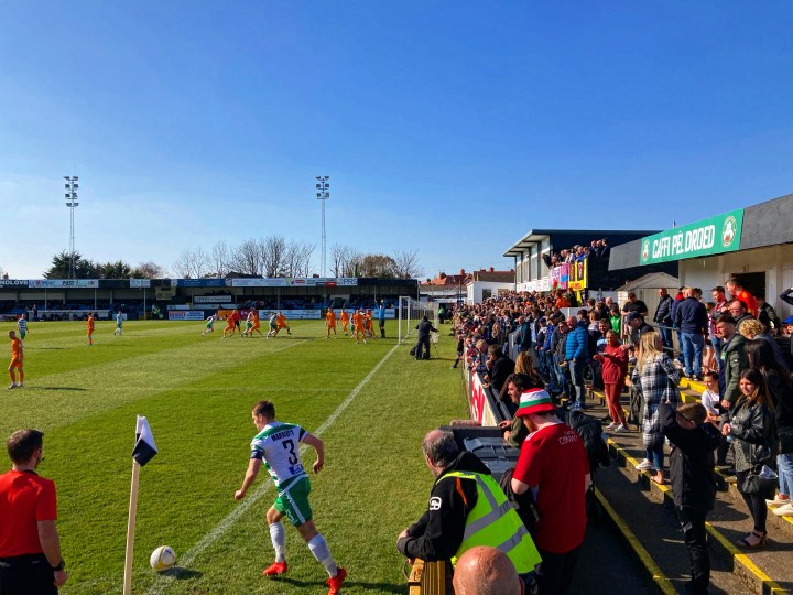 The New Saints number three takes a corner against Colwyn Bay in front of a packed terrace behind the goal at Rhyl's Belle Vue ground