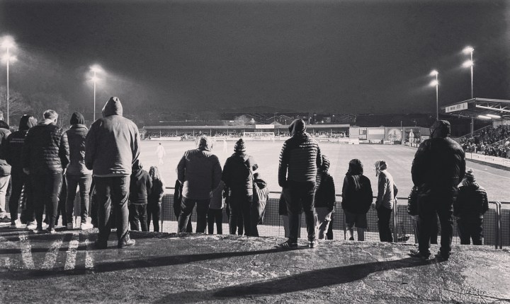 Wales supporters in hoods stand out in the rain during a match between Wales C and England C at Caernarfon Town's Oval