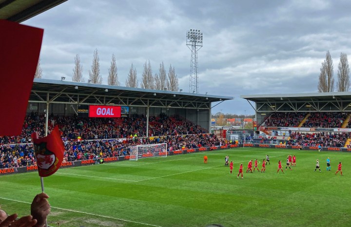 Fans and players celebrate a goal for Wrexham women at a packed Racecourse Ground