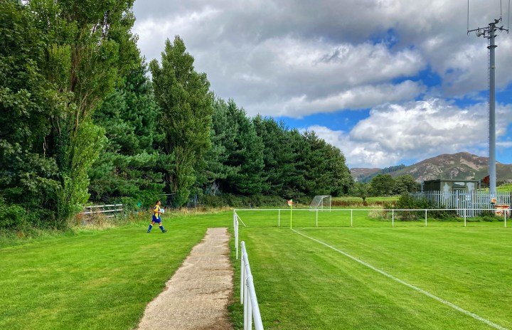 A Penmaenmawr Phoenix player fetches the ball to take a corner kick against Llandyrnog United at Cae Sling