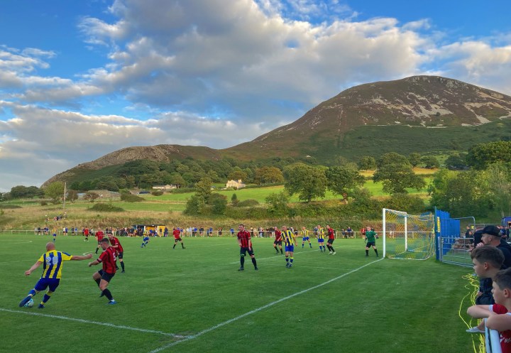 Penmaenmawr Phoenix's number 20 crosses te ball with his left foot during a match against Llanfairfechan Town at Phoenix' Cae Sling ground with its mountain backdrop