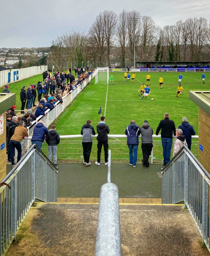 Looking down the steps from the turnstiles at Nantporth onto the field where Bangor 1876 take on Porthmadog in front of a sizeable crowd