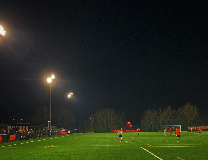 A Penmaenmawr Phoenix player crosses the ball under the floodlights at Treborth