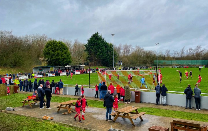 A packed crowd at Buckley Town's ground The Globe watch on as a Connahs uay Nomads player heads for goal