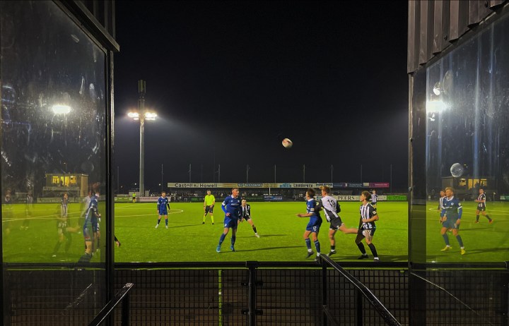 Players from Llandudno and Airbus challenge for an aerial ball at the former's Maesdu Park under floodlights