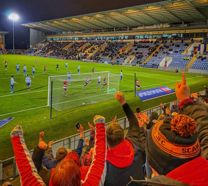 Doncaster Rovers supporters celebrate as Tom Anderson, also celebrating on the pitch, puts Doncaster Rovers 3-1 up at Colchester United