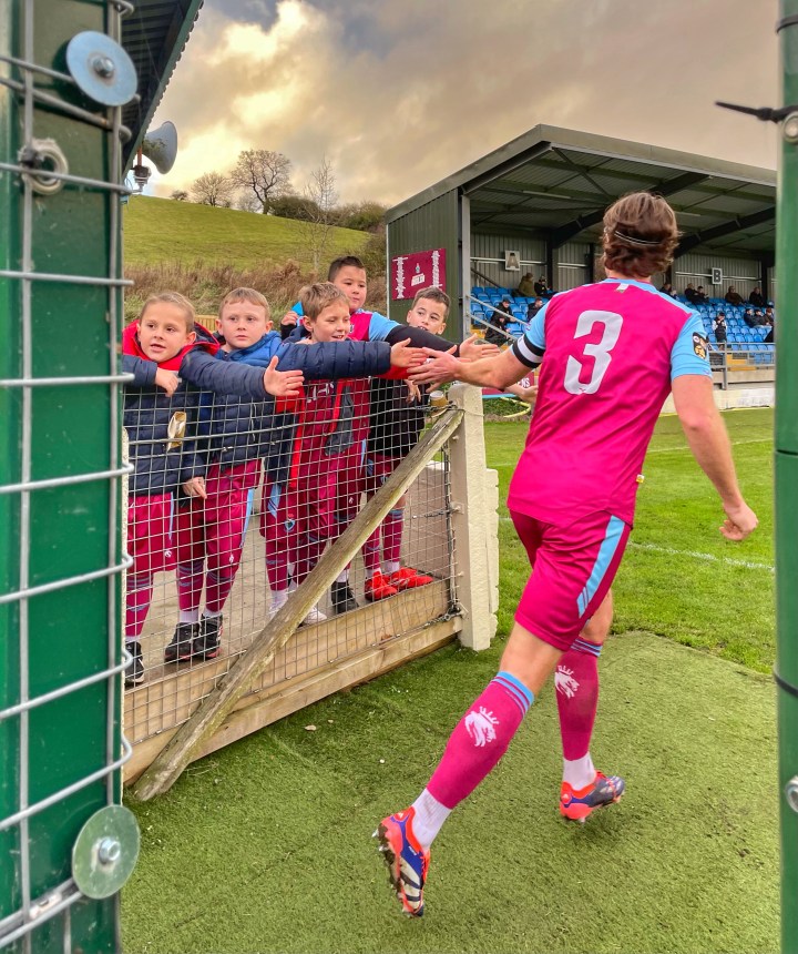 Colwyn Bay's captain high fives a row of young fans as he heads out the tunnel for the second half