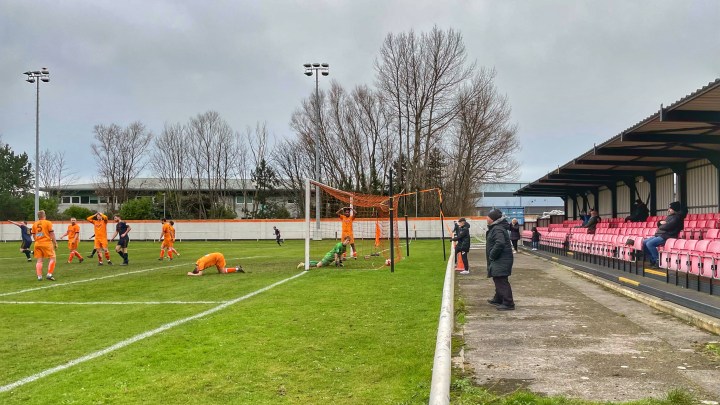 Conwy defenders and goalkeeper stand and lie dejected after conceding a goal to Trearddur Bay