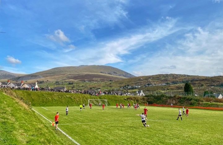 A Deiniolen defender takes a free-kick in front of the picturesque mountainous backdrop to Deiniolen's home ground