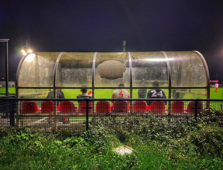 Llandudno Amateurs subs watch on from the perspex dugout as their team take on Penmaenmawr Phoenix