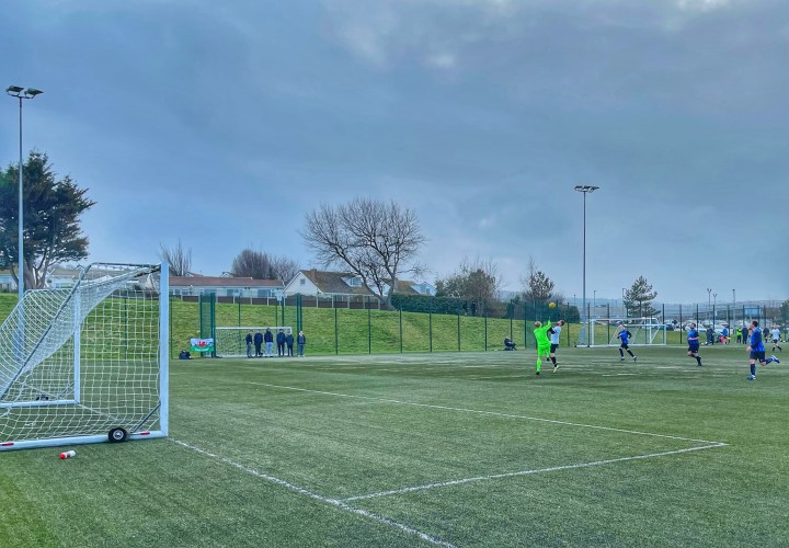 A Llysfaen striker and the Penrhyn Bay goalkeeper challenge for the ball