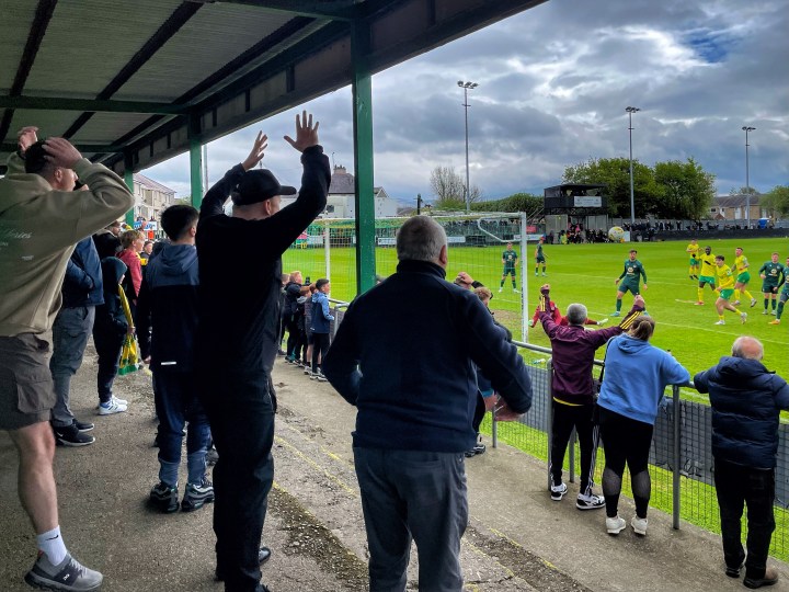 Caernarfon fans on the terrace behind the goal can't believe their team has missed as the ball spins wide of the goal