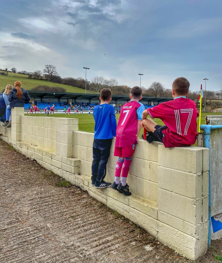 Three young Colwyn Bay fans watch their team play against Caersws