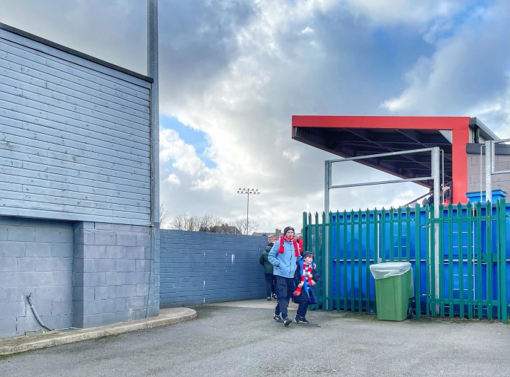 Two Doncaster Rovers fans – father and son – leave the stand at Accrington Stanley's stadium