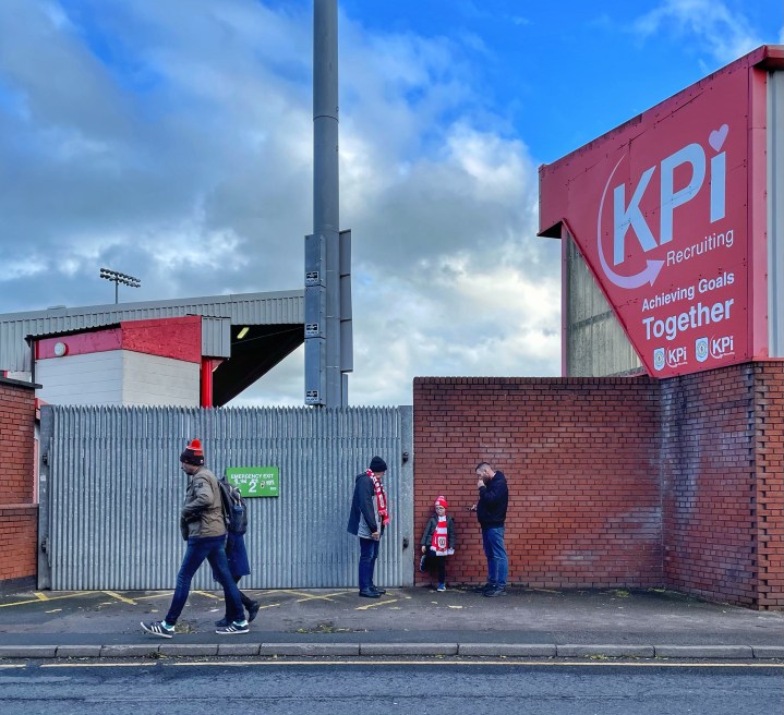 A young fan stands with older relatives outside the ground ahead of Crew Alexandra's FA Cup tie with Doncaster Rovers.
