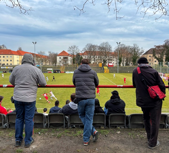 Supporters of SV Lichtenberg 47 lean against a barrier to watch their team's match against SV Siedenbollentin in East Berlin.