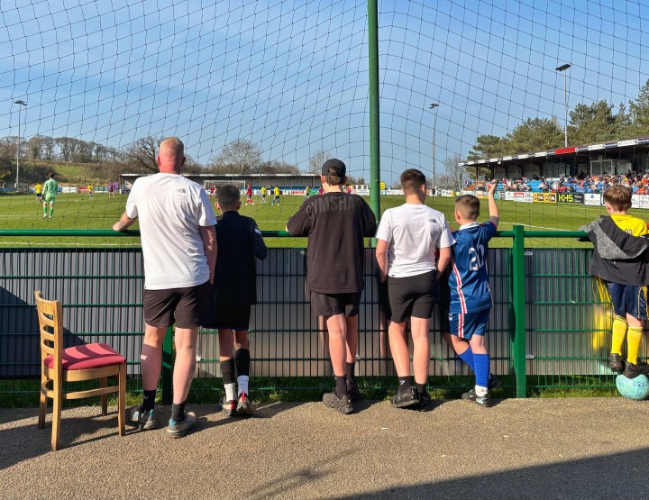 Bangor City fans peer through the pitch-side netting to watch their team defeat Penmaenmawr Phoenix in the FAW Welsh Amateur Trophy semi-final at Colwyn Bay.